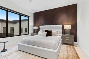 Bedroom with an accent wall, light wood-style floors, and baseboards