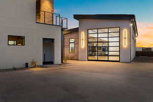 Back of property at dusk featuring stone siding and stucco siding