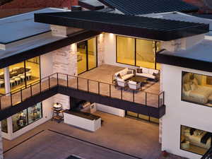 Rear view of property featuring an outdoor hangout area, a patio, stone siding, and an outdoor kitchen