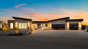 Contemporary home featuring an attached garage, stone siding, and driveway