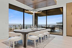 Dining space with a wall of windows, a water view, light wood-style flooring, and baseboards