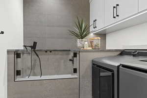 Washroom featuring cabinet space and washing machine and clothes dryer