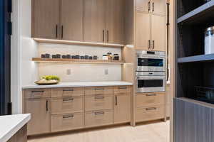 Kitchen featuring double oven, open shelves, and light countertops