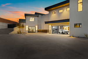 Back of house at dusk featuring stone siding and stucco siding