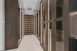 Walk in closet with light carpet and visible vents