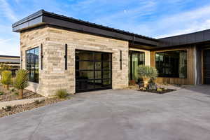 Doorway to property with driveway, stone siding, and an attached garage