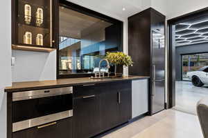 Bar with oven, a sink, finished concrete flooring, and dishwasher