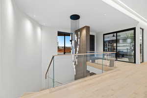 Hallway with wood finished floors, an upstairs landing, and recessed lighting