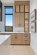 Kitchen featuring baseboards, light brown cabinets, light wood finished floors, and decorative backsplash