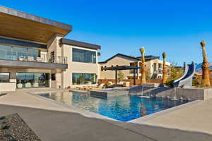 View of pool featuring a pool with connected hot tub, a water slide, and a patio