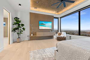 Bedroom featuring ceiling fan, wood finished floors, a raised ceiling, and baseboards