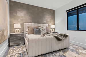 Bedroom featuring an accent wall, tile walls, and baseboards