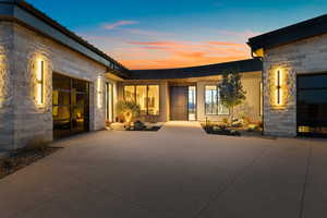 Rear view of house featuring an attached garage, driveway, a patio, and stone siding