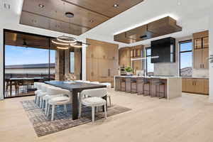 Dining space featuring a tray ceiling, a ceiling fan, a wealth of natural light, and light wood-style floors