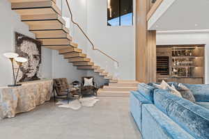 Living area featuring finished concrete flooring, stairs, and a high ceiling