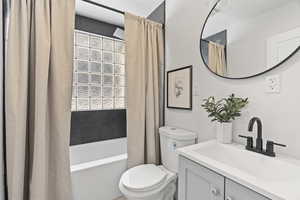 Full bathroom with vanity, shower / bath combination with curtain, and toilet