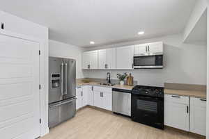 Kitchen featuring white cabinetry, appliances with stainless steel finishes, sink, and light hardwood / wood-style flooring