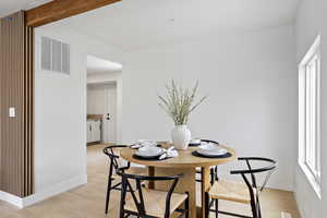 Dining space with beam ceiling and light hardwood / wood-style flooring