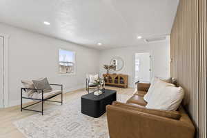 Living room with light hardwood / wood-style floors and a textured ceiling