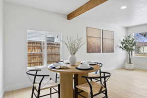 Dining area with beam ceiling and light hardwood / wood-style floors