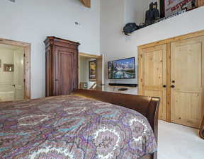 Carpeted bedroom featuring a high ceiling