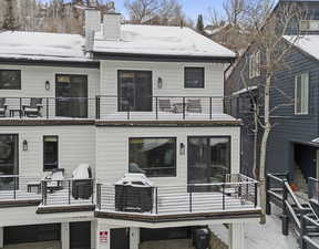 Snow covered back of property featuring a balcony