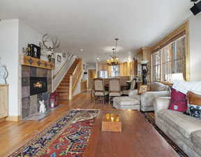 Living room with a tiled fireplace, a notable chandelier, and light wood-type flooring