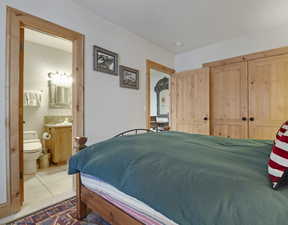 Tiled bedroom featuring a closet and ensuite bathroom