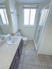 Bathroom featuring tile patterned floors, vanity, toilet, and a shower with shower door