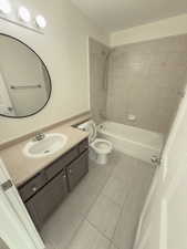 Full bathroom with vanity, tiled shower / bath combo, tile patterned floors, and toilet