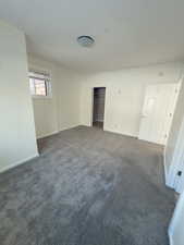 Unfurnished bedroom featuring a closet and dark colored carpet