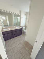 Bathroom featuring vanity, a shower with shower door, tile patterned floors, and toilet