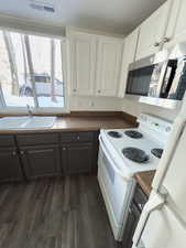 Kitchen with white cabinetry, white electric stove, and sink