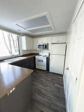 Kitchen featuring sink, white appliances, dark wood-type flooring, and white cabinets