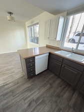 Kitchen with white dishwasher, sink, white cabinetry, and kitchen peninsula