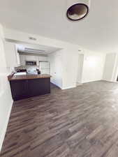 Kitchen with sink, white appliances, dark wood-type flooring, white cabinetry, and kitchen peninsula