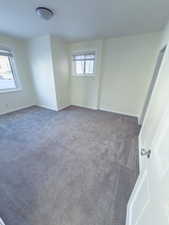 Unfurnished room featuring dark colored carpet