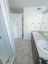 Bathroom with vanity, a shower with shower door, and tile patterned flooring