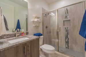 Bathroom with vanity, toilet, and a shower with shower door