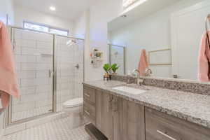 Bathroom featuring vanity, walk in shower, and toilet