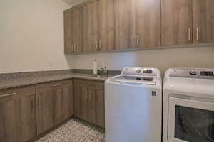 Laundry area with sink, cabinets, washer and dryer, and light tile patterned flooring