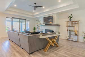 Living room featuring light hardwood / wood-style floors, a raised ceiling, and ceiling fan