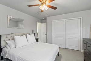 Bedroom featuring light colored carpet, ceiling fan, and a closet