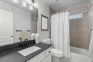 Full bathroom featuring vanity, shower / bath combination with curtain, and toilet