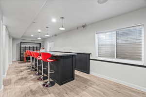 Bar featuring pendant lighting, light stone countertops, and light wood-type flooring