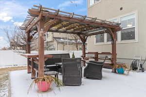 Snow covered patio with a pergola