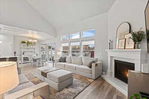 Living room with hardwood / wood-style flooring, a notable chandelier, and high vaulted ceiling