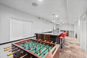 Game room with wet bar and light wood-type flooring