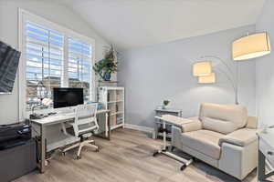 Office space featuring vaulted ceiling and light wood-type flooring