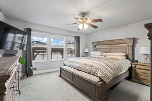 Bedroom with light colored carpet, a textured ceiling, and ceiling fan